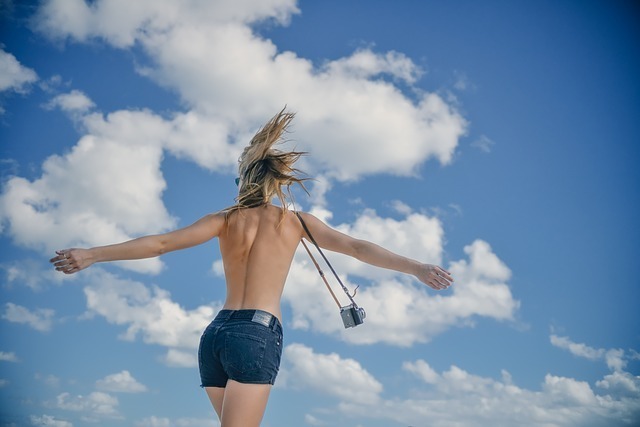 青空に向かって手を広げる女性