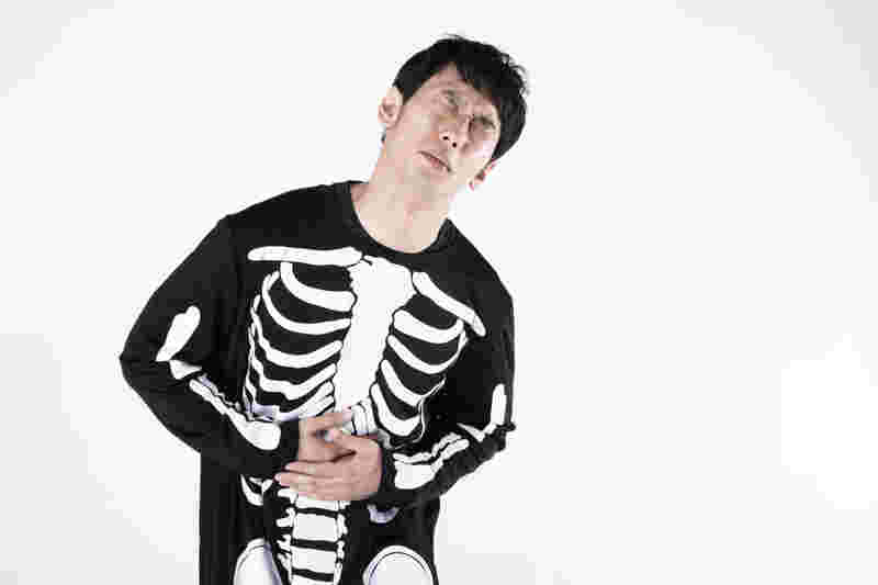 お腹の具合が悪い骨の柄の服を着た男性