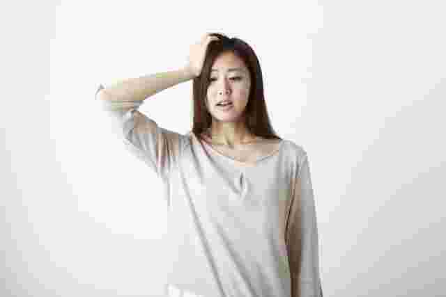 頭に手を当てる女性