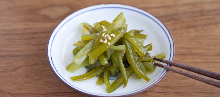 白いお皿にのった茎わかめん箸でつかむところ