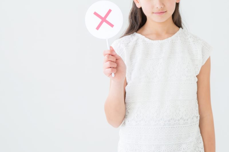 女の子がバツの札を持っている