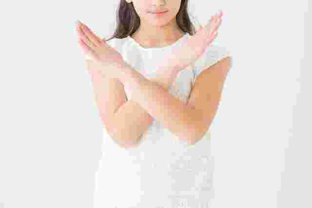 腕でバツを作る女性