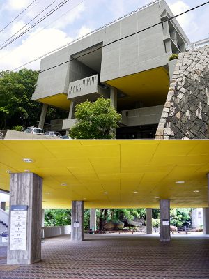 (上)天神山文化プラザ西側外観。建物が張り出した部分がピロティーになっている。正面中央部は外階段。手すり壁に刻まれた上下互い違いの模様が、行き交う人の動きを表現している(下)ピロティー。正面に天神岩が祀られている。右手奥にホール、手前に展示室の入り口がある。左手の階段はかつての図書館と日米文化センターに続く。今はいずれも展示室になっている