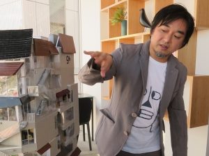 ナインアワーズ浅草について説明する、建築家の平田晃久氏。「ナインアワーズでは、カプセルのフロントパネルにスチールのプレートを使ってシャープなイメージにすることが多いのですが、ナインアワーズ浅草では木目のある木を使いました。サインの照明も色温度を低めにして、まわりの感じに合わせています。浅草のまち、FUGLENとの調和を考えながら、ナインアワーズのデザインチームとディスカッションを重ねて設計を進めました」