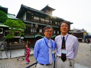 ▲2019年1月15日から保存修理工事に入った『道後温泉本館』。「道後温泉は、道後のシンボルであり松山の宝。工事前・工事中・工事後の3つの姿を見てみたいと思っていただけるような展開を考えています」(松山市道後温泉事務所の山下勝義さん(右)と寺井修二さん(左)談)