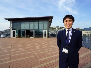 ▲長崎県 企画振興部 地域づくり推進課 移住推進班の長崎屋伸州さん。「実は僕自身も大学進学のときに一度地元を離れて福岡へ出たので、県外へ出たいと考える若者たちの気持ちはわかります。でも“長崎屋”という名前を背負っていることもあって(笑)、僕は大学卒業後に地元・長崎へ戻る決断をしました。“長崎県人は道を聞いたら教えてくれるやさしい人が多い”とよく他県の方から言われます。鎖国時代に国の窓口だった歴史もあり、外から来る人やモノを受け入れやすい文化があると感じています」と長崎屋さん(昨年1月に新築移転した長崎県庁屋上にて撮影)