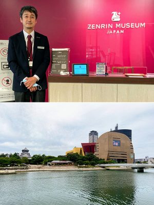 上:ゼンリンミュージアムのエントランスで、館長の佐藤渉さん。館名の上に描かれたシンボルマークは、地図を描いて丸めた羊皮紙と、方角を指し示す星と月がモチーフ。未知の土地を求めて航海する、船のイメージも重ねられている </br>下:ゼンリンミュージアムのあるリバーウォーク北九州(写真右手)。建物の設計は、六本木ヒルズなども手掛けたアメリカの建築家ジョン・ジャーディ。写真左手には小倉城天守閣が見える
