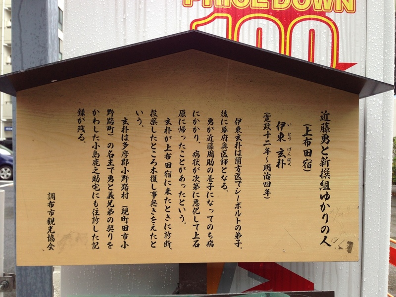 【上布田宿の案内板】<p>近藤勇が近藤周助の養子になったのちに病にかかり、病状が悪化した。その時、蘭方医の伊東玄朴が上布田宿にやってきて、近藤勇を診療した結果、見事回復したという話。</p>