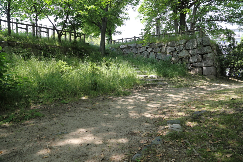【淀城本丸北西の石垣と明治天皇行幸の石碑】<p>1868年、明治天皇は海軍検閲のため大阪行幸されたが、その際に淀城に宿泊したとのこと。詳しくは京都市HP「<a>明治天皇御駐蹕址</a>」に書いている。</p>
<p>明治天皇行幸の石碑は淀城本丸北西の石垣上にある。<br>写真の右上に立っている石碑が分かるだろうか。</p>