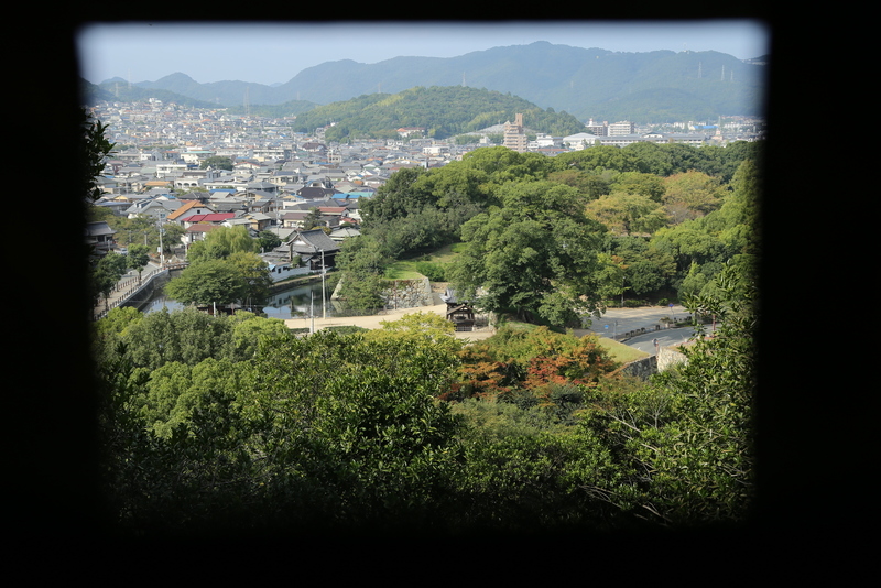 <p>姫路城百間廊下の狭間から西側を守る清水門を撮影。<br>ちょっと分かりにくいが、中央の石垣が清水門。道路拡張でだいぶ変形しているが、石垣自体は結構残っている。</p>
<p>やはり、闇雲に狭間を作っているのではないんでしょうね。</p>