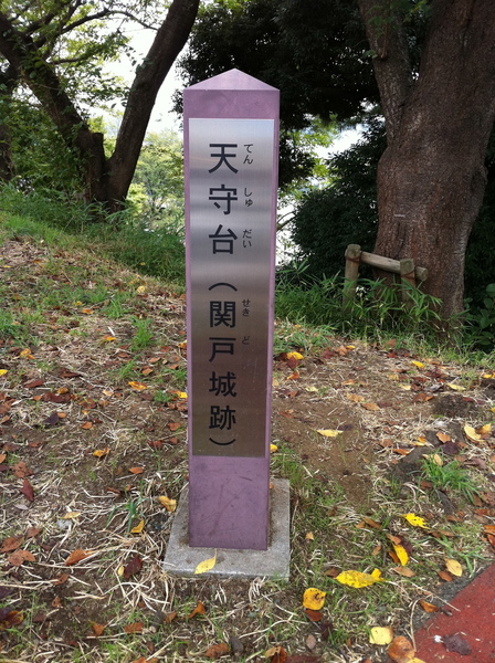 【関戸城跡の「天守台」標柱】<p>鎌倉街道から東へ坂道を登ってきて、最高地点を探していたら、この関戸城跡の「天守台」標柱に行き着いた。</p>
<p>案内板によると、金毘羅宮（琴平社）付近を「天守台」というとのこと。北側の多摩川方面への視界が開けているので、物見台的な施設があったと考えられている。</p>