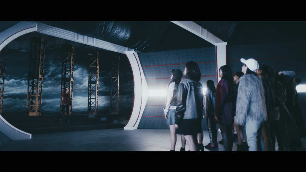 NMB48 16thシングル「僕以外の誰か」の公式MVより。冒頭で、センターの山本彩がメンバーらに向かってマイクを投げるシーンが流れる。