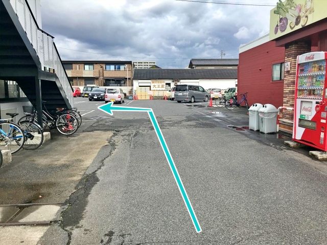 通路を進み、白い建物沿いに左折してください