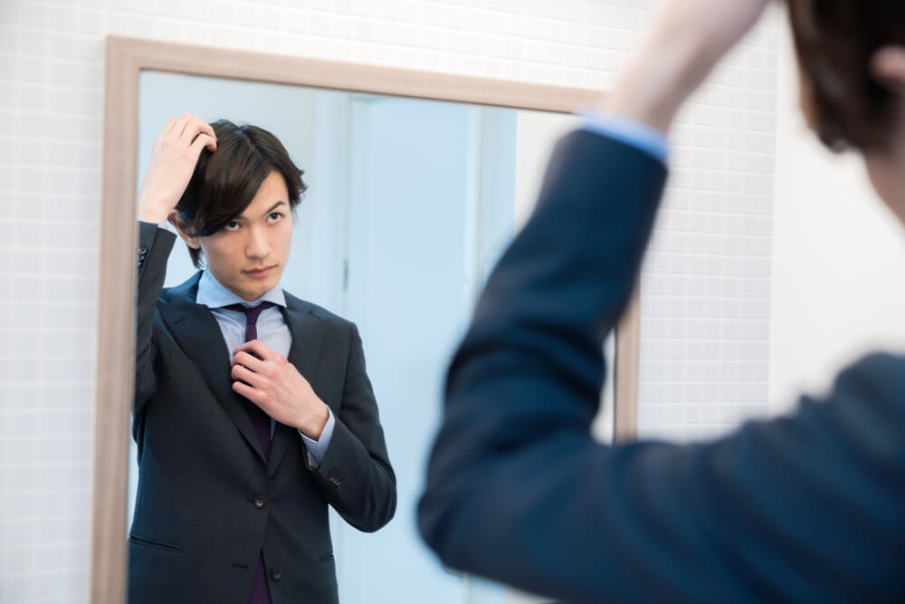 鏡で頭皮をチェックする男性