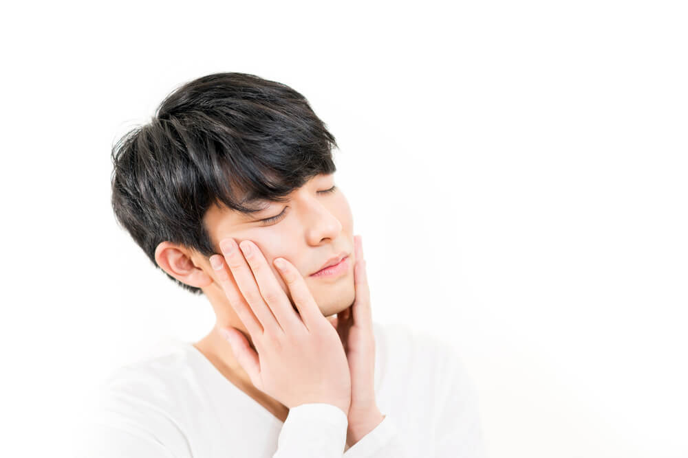 頬に両手を当てる男性