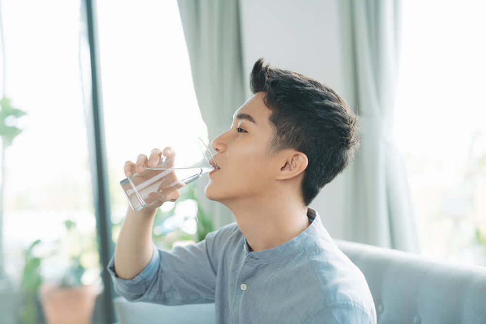 コップで水を飲む男性