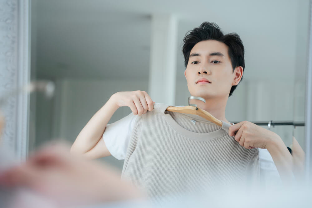 鏡を見ながら服を選ぶ男性