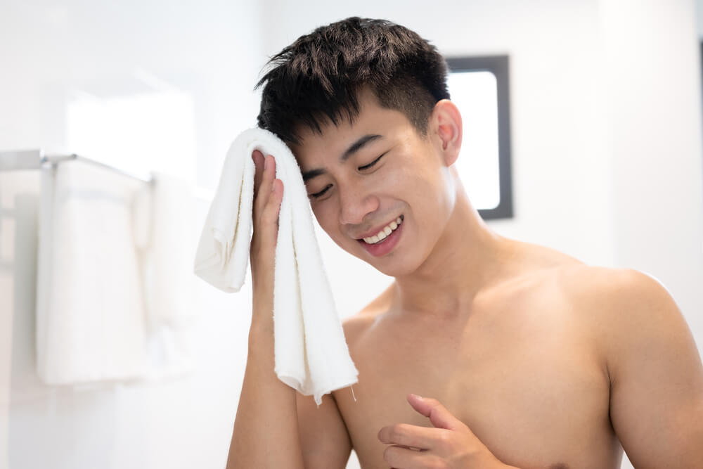 タオルで顔を拭く男性