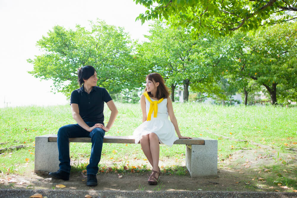公園のベンチに座って話をする男女
