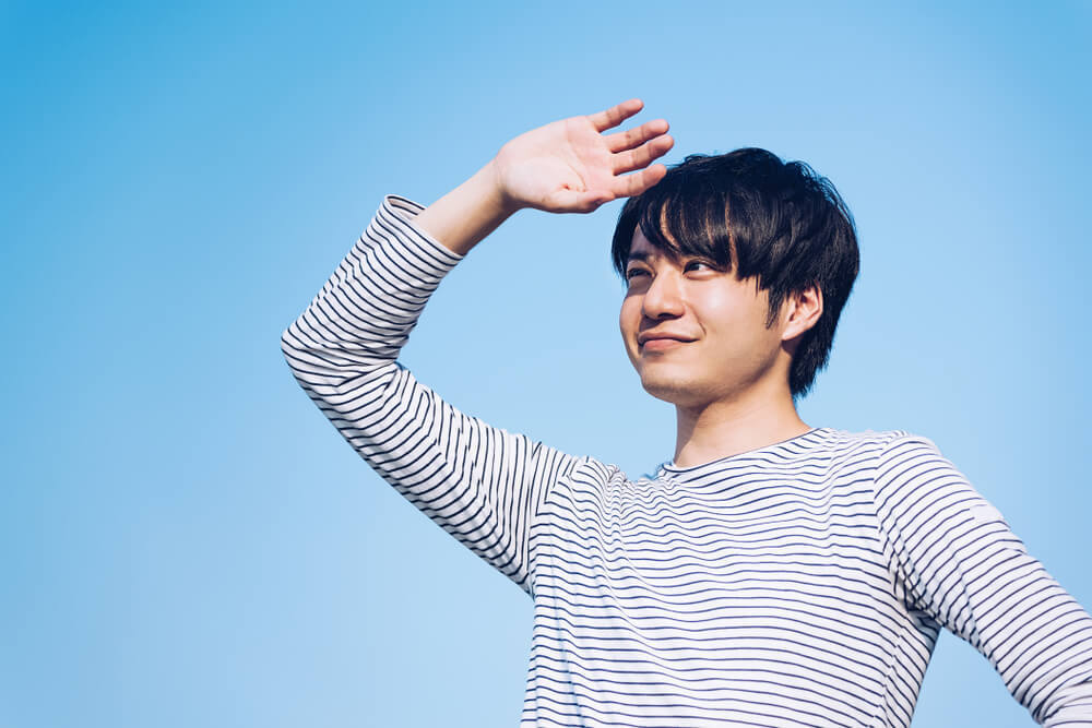 日差しに手をかざす男性