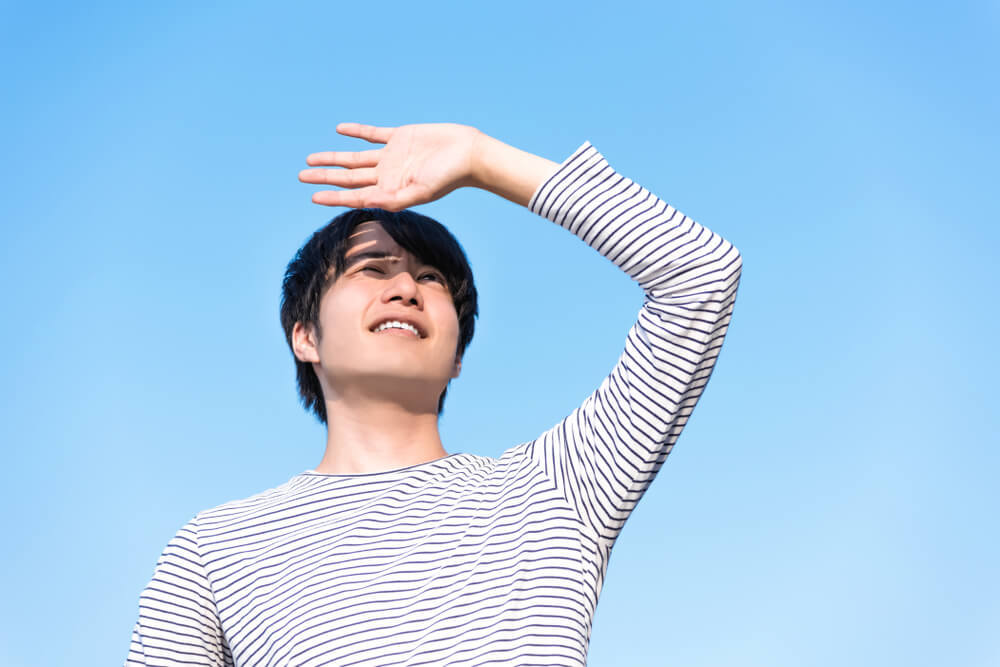 日差しに手をかざす男性
