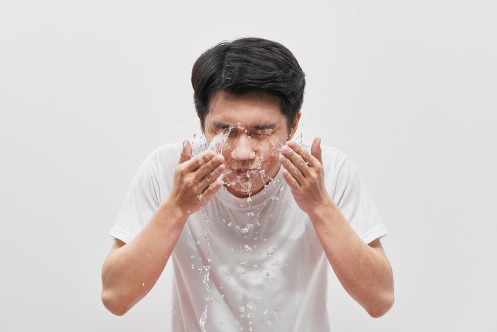 水しぶきを上げて顔を洗う男性