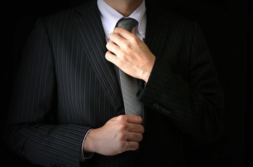 ネクタイをしめようとする男性