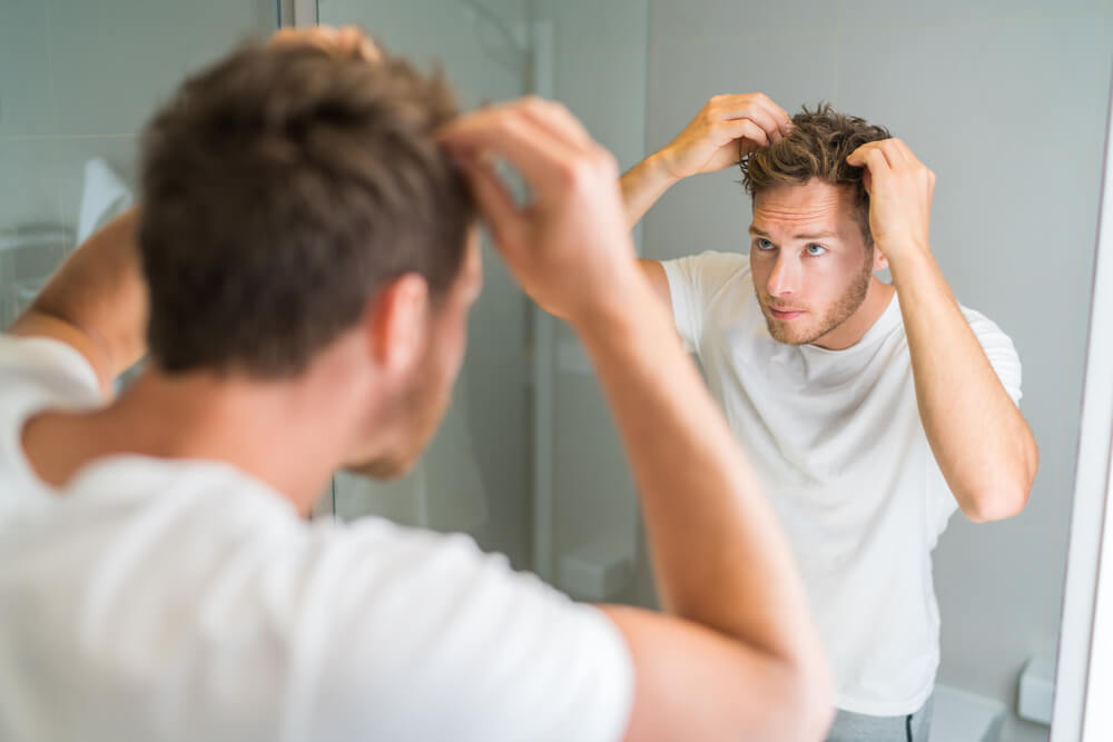 鏡の前で髪を整える男性