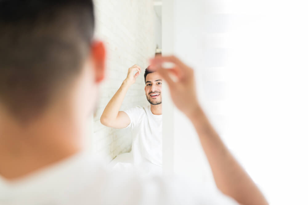 鏡を見て髪を整える男性