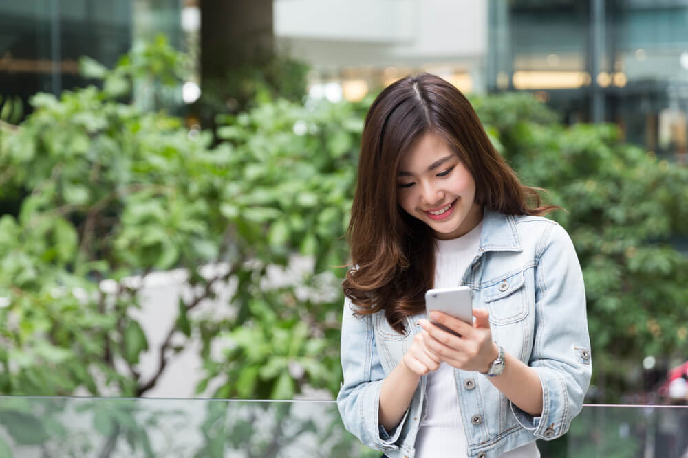 スマートフォンを見て微笑む女性