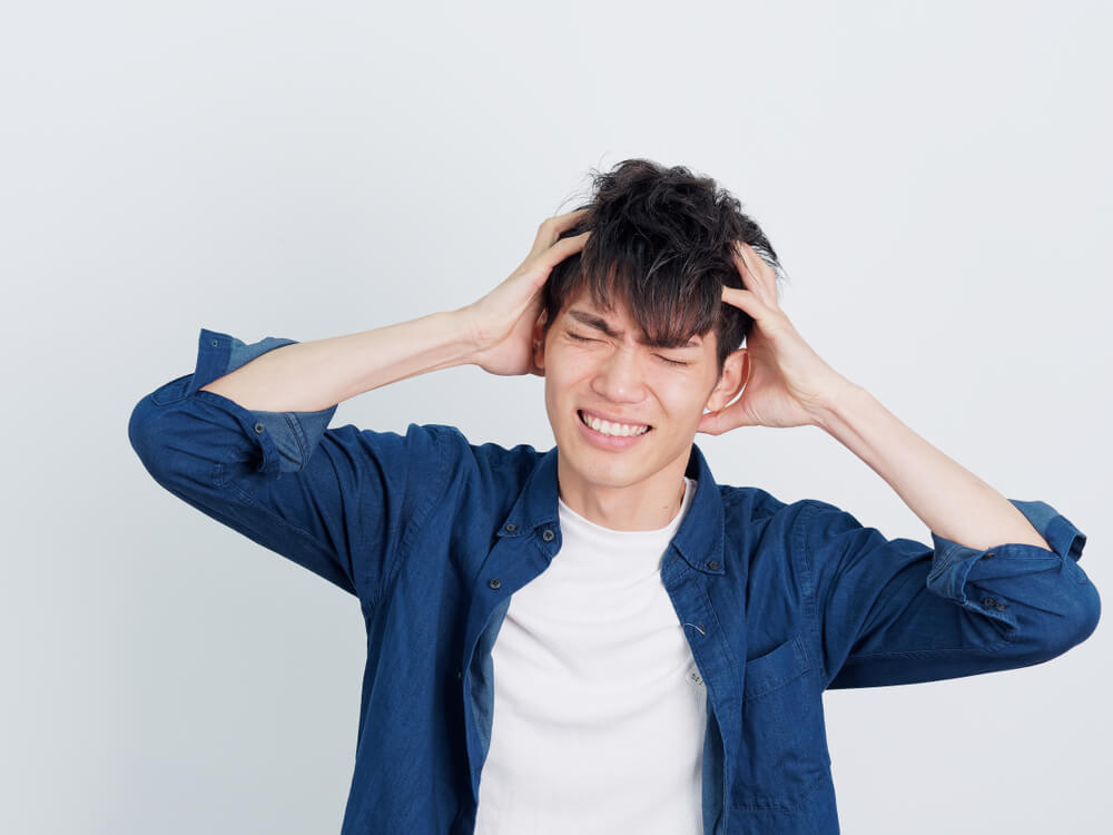 両手を頭に当てる男性