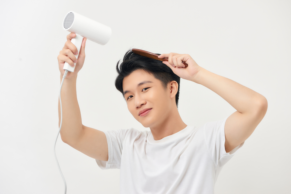 髪をとかしながら乾かしている男性
