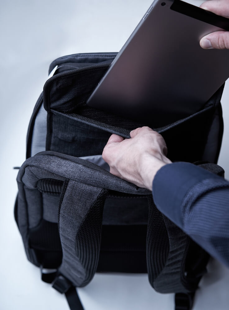 リュックにタブレットを入れる男性