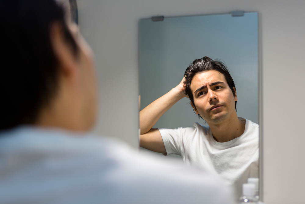 鏡を見て悩んでいる男性