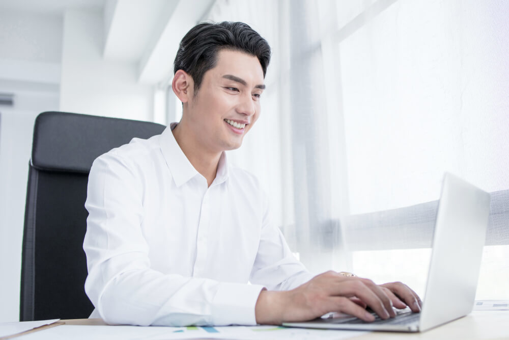 白いシャツを着てPCを操作する男性