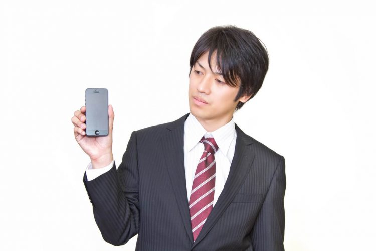 スマホの裏を見せる男性
