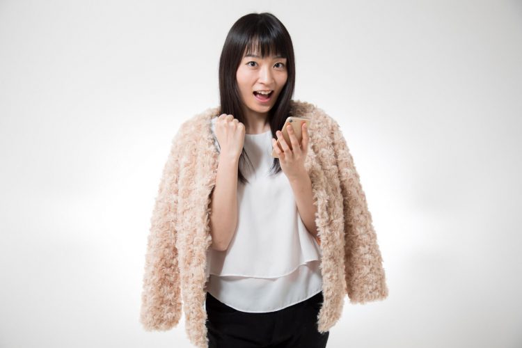 スマホを見てガッツポーズをする女性