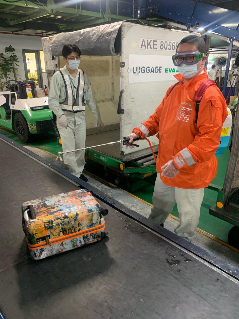 桃園機場人員右邊橘色防護衣噴灑酒精消毒旅客行李