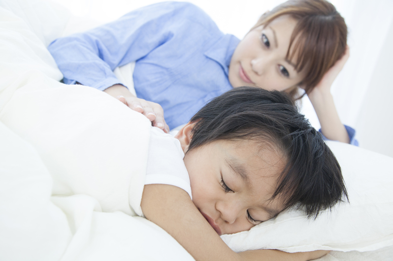 寝ている子どもと、見守る保護者