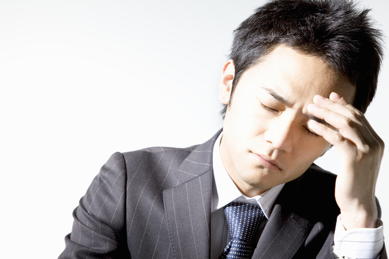 頭を押さえる若い男性