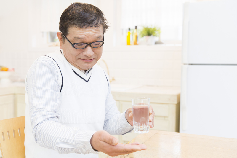 薬を飲むシニア男性