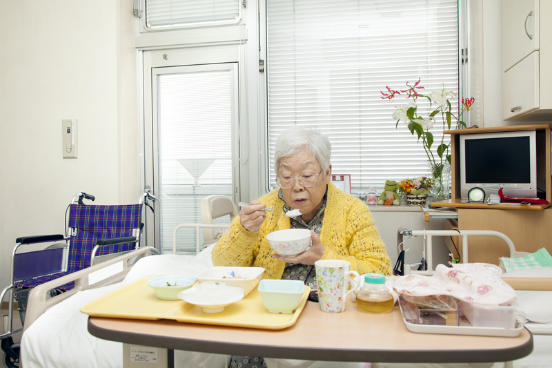 入院中、ベッドで食事をしている高齢者