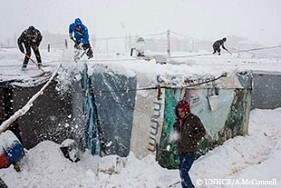 7日早朝、吹雪の中レバノンのベッカー高原の非公式テント居住地にあるシェルターの雪かきをするシリア難民。