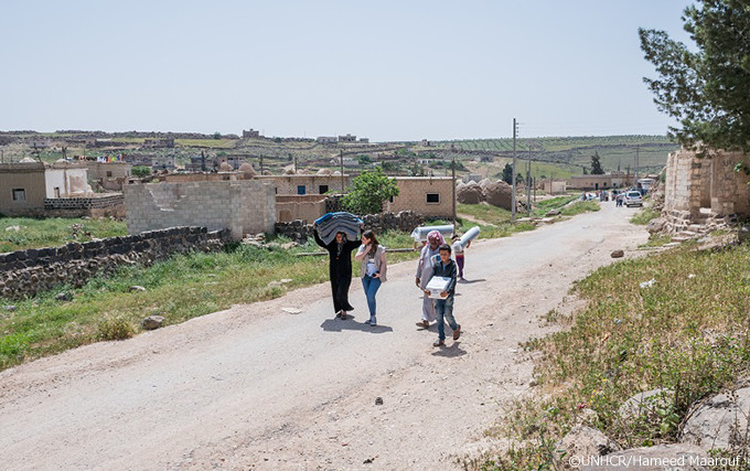 写真:救援物資を運ぶフセインとファティマ、UNHCRの職員