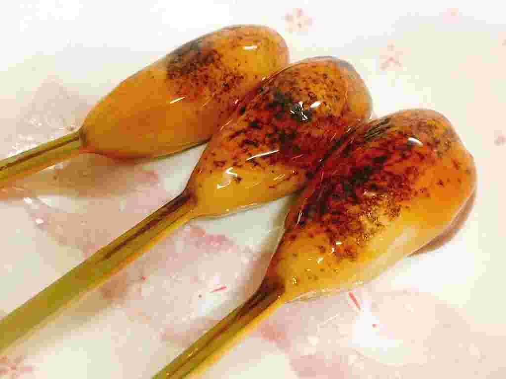 あぶっている3本のツヤのあるみたらしだんごが美味しくみえる