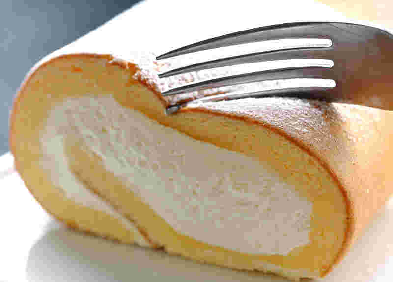 クリームがたっぷり入ったロールケーキをフォークでカットしようとしている