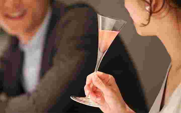 女性がカクテルを持ちながら男性と飲んでいる
