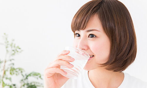 コップで水を飲む女性