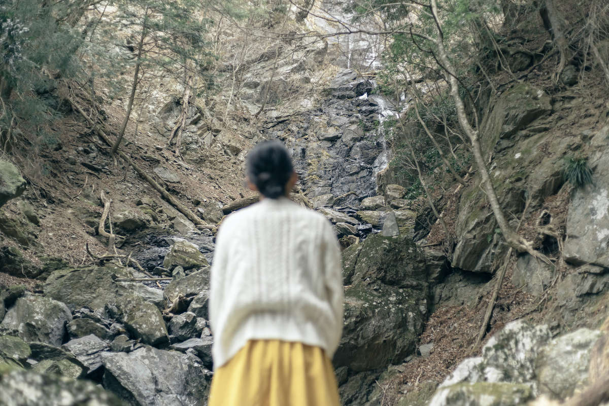 藁科川の源流近くにある「福養の滝」を見ている女性の写真