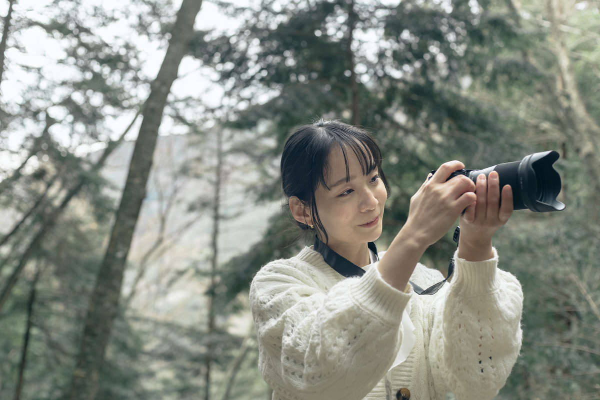 藁科川の源流近くにある「福養の滝」の景色をカメラで撮影している女性の写真